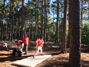 A man throwing a disc at the disc golf course