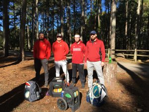 Four men standing beside their disc golf gear before playing disc golf